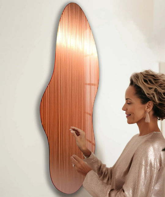 A woman admires a bronze irregular glass wall art piece, its vertical lines creating a captivating visual rhythm.