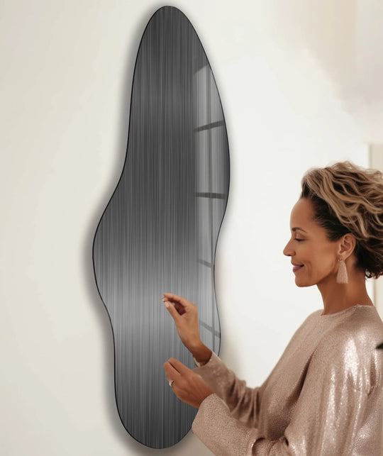 A woman admires an irregular, asymmetrical black glass wall art print with abstract geometric elements.