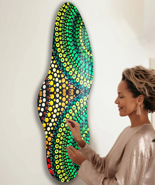 A woman admires a custom glass art piece with a dark background featuring vibrant green and yellow dot patterns.