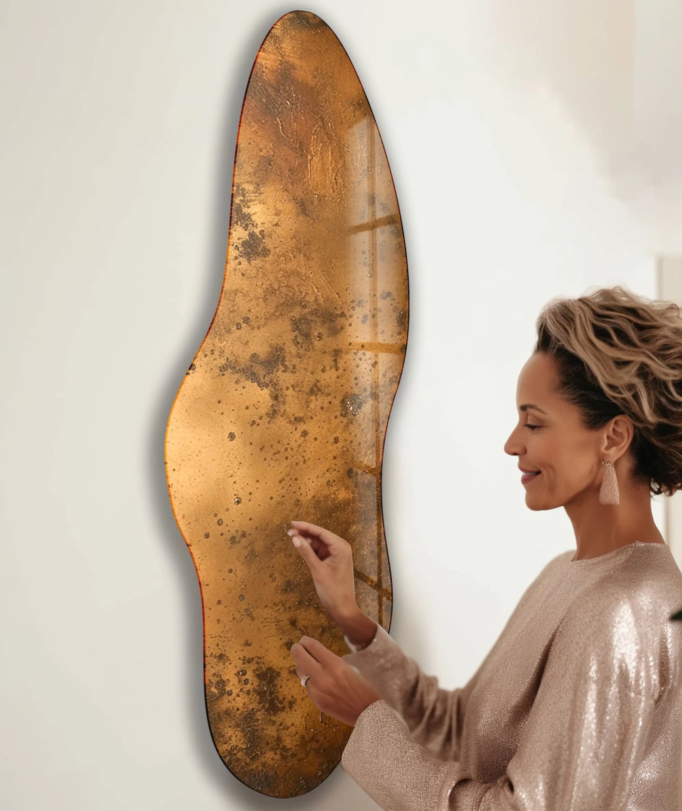 A woman admires a bronze-colored abstract irregular glass wall art featuring a rich transition of earthy tones on wall art prints.