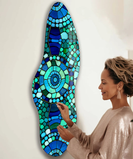 A woman admires the intricate layering effect and concentric circular design of this irregular mosaic green and blue glass wall art, a stunning example of best glass art.