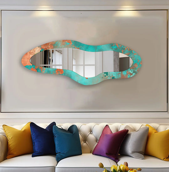 The focal point is the green asymmetrical full length mirror for wall decor hanging above a white tufted sofa with colorful throw pillows.