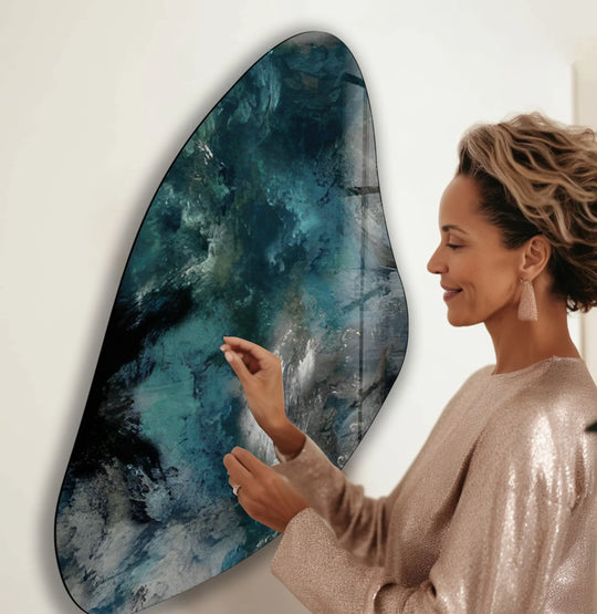 A woman admires cool-toned, deep blue and teal abstract glass printing with a moody color temperature.