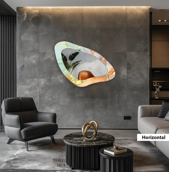 An asymmetric mirror showcases an irregular abstract design in light green orange and gold reflecting plant leaves displayed horizontally