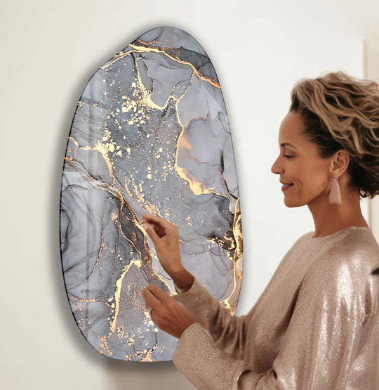 A woman admires the organic forms and gold veining of abstract grey alcohol ink wall prints.