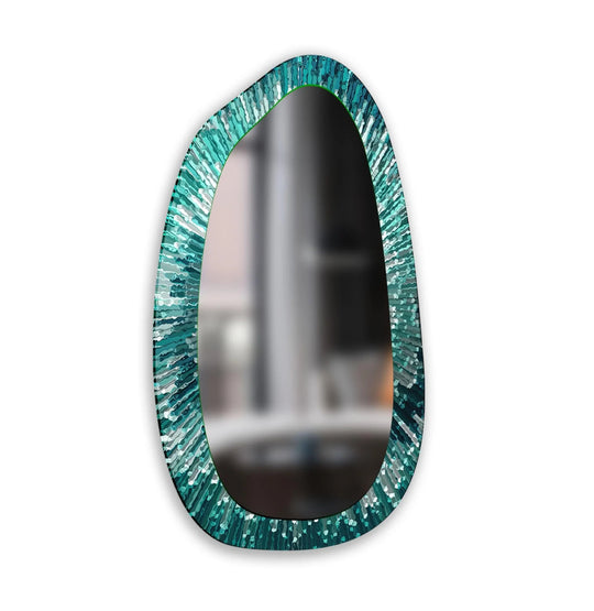 Asymmetric mirror with a modern abstract green and teal patterned frame vertically oriented reflecting a blurred room