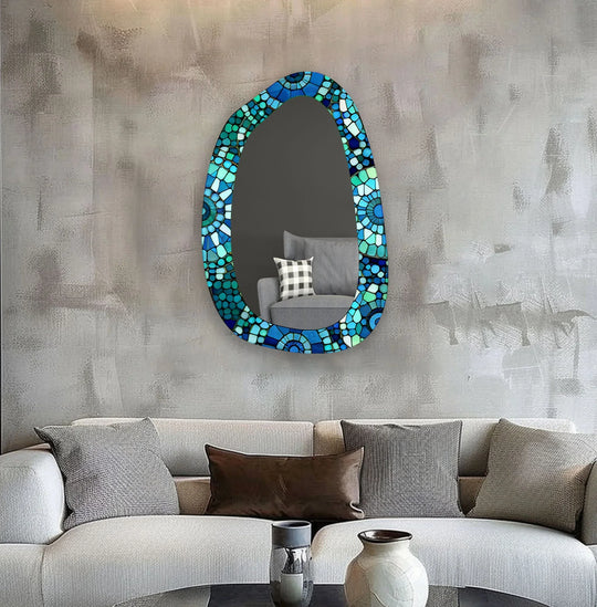 Textured grey backdrop highlights the green and blue mosaic frame of a large glass wall mirror, offering a sleek, modern mirror style.