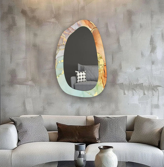 An asymmetric tempered glass wall mirror with gold accents and abstract artistic swirling orange green and white colors reflecting a gray couch