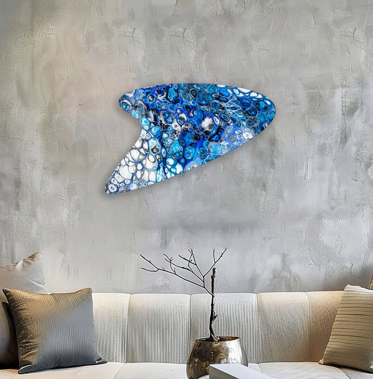 Abstract blue marbled glass wall art in a unique shape adorns a textured wall.