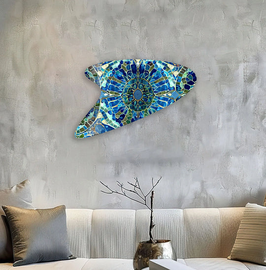 Textured concrete wall with a vibrant blue and green mosaic glass wall art decor piece reflecting light.