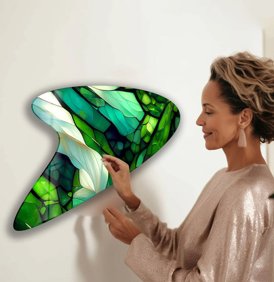 A woman touches a vibrant, cool-toned green stained glass art painting with a modern, irregular shape.