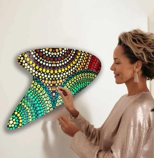 A woman adjusts a green mosaic abstract decorative wall art piece with vibrant, iridescent dot patterns.