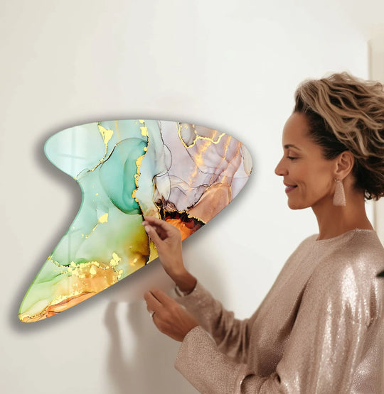 A woman admires the glossy, textured surface of a green alcohol ink irregular glass wall art piece with delicate gold accents.