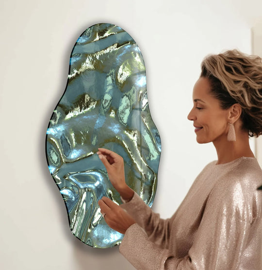A woman admires a piece of decorative wall art where metallic green glass transitions from deep emerald to shimmering silver.