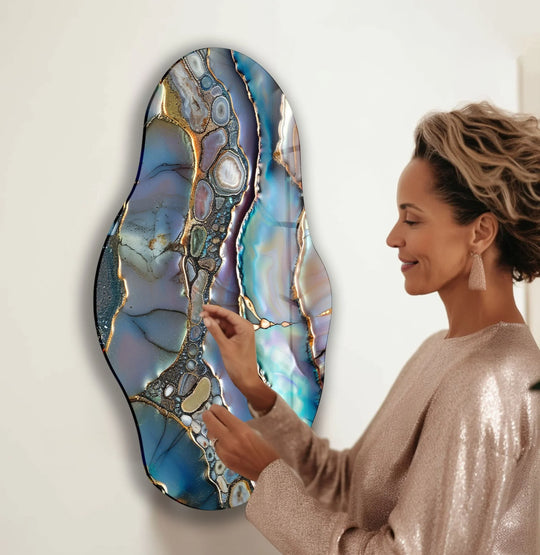 A woman admires the negative space surrounding a vibrant, abstract purple glass art piece with golden accents.