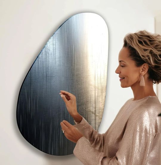 A woman admires a unique modern wall decor piece, a metallic gray abstract glass art with flowing lines.