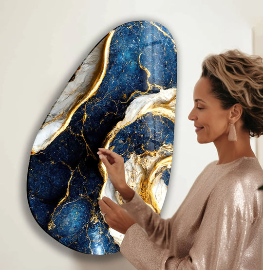 A woman's hands gently touch vivid blue marble glass wall art decor with gold veining.