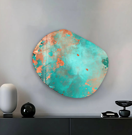 An abstract green and copper glass art piece with a softly rounded, irregular edge hangs on a gray wall.