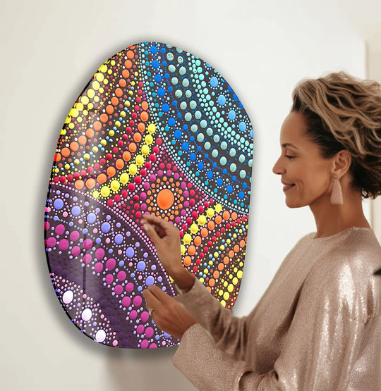 A woman admires a vibrant, oval mosaic rainbow color glass wall art piece, showcasing colorful dot patterns.