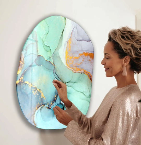 A woman's hand touches a vibrant turquoise and gold abstract glass art piece.