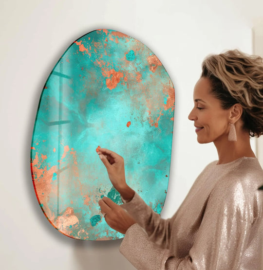 A woman admires the translucent, layered effect of a teal and copper glass wall art decor piece.