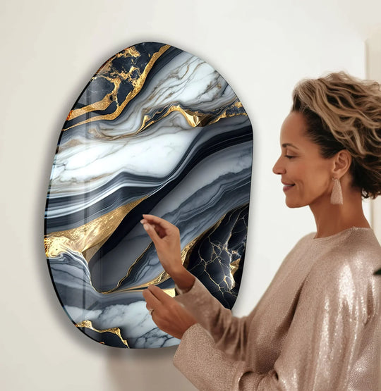 A woman admires the rich marbling and shimmering gold veins of this oval glass wall art, a statement piece with exquisite material quality.