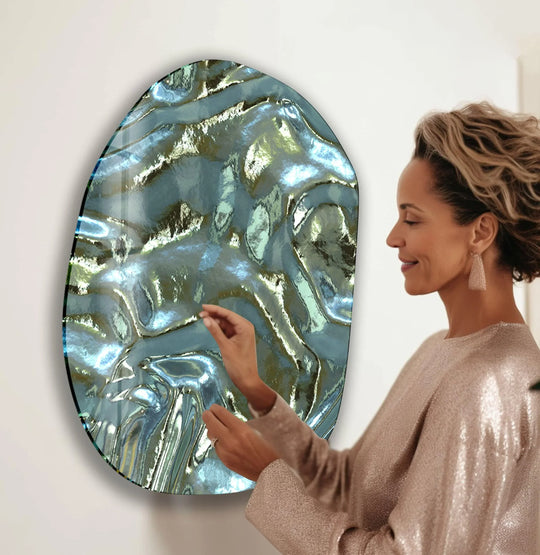 A woman admires the swirling blue and green patterns of a large, abstract glass art painting.