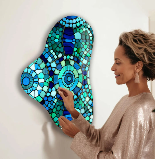A woman admires a unique modern wall decor of abstract blue and green mosaic glass art.