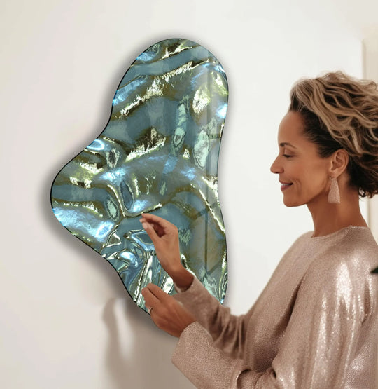 A woman admires iridescent metallic green glass wall art, its asymmetrical shape emphasizing a captivating layering effect in this print wall art.