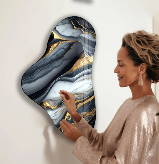 An asymmetric glass wall artwork with dynamic geometric shapes in gold and gray marble patterns adorns a white wall.
