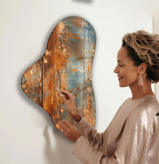 A woman admires a striking asymmetrical glass wall art piece with fiery rust and cool blue tones, representing the best glass art.
