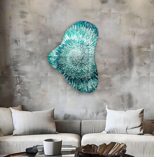 An abstract, asymmetrical turquoise glass wall art piece, like a burst of radiant light, hangs on a textured wall.