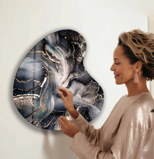 A sophisticated irregular glass wall art print featuring a dominant deep navy, charcoal, and opulent gold abstract watercolor design.