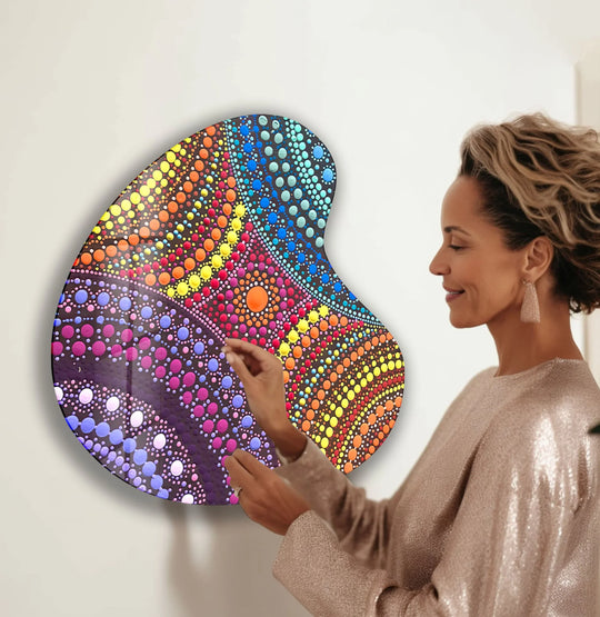 A woman admires the glossy finish of a purple mosaic irregular glass wall art with vibrant multicolored dots.