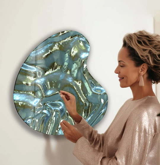 A woman admiring an irregular green and grey abstract glass wall art piece.