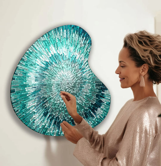A woman admires a turquoise abstract spiral glass wall art piece with a textured, layered surface.