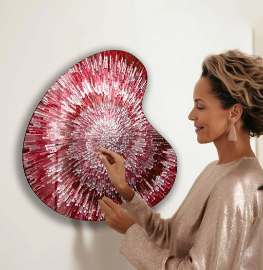 A woman admires a striking red abstract style irregular glass wall art, a piece of unique modern wall decor.