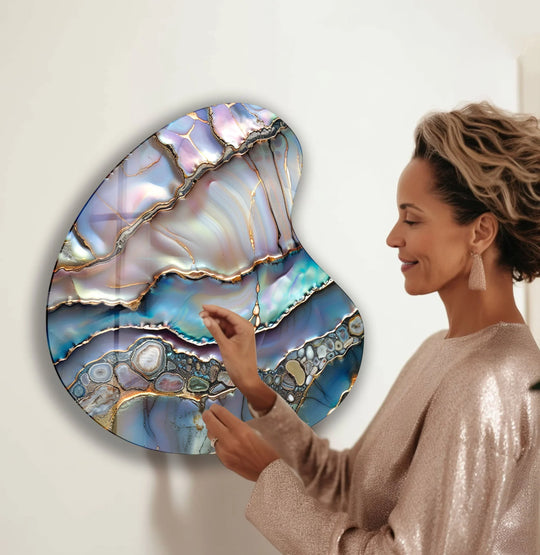 A woman admires a detailed, abstract purple glass wall art with metallic gold accents and iridescent hues.