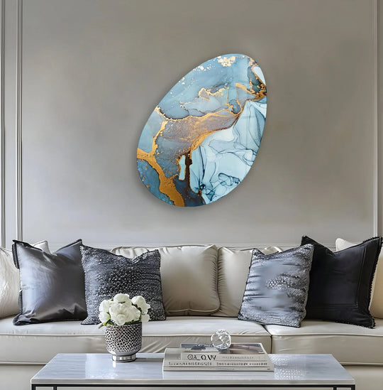 A modern oval glass wall art featuring abstract blue watercolor with gold accents, casting soft shadows on the textured wall.