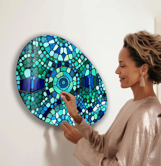 A woman admires a striking oval mosaic glass printing artwork, its colors transitioning beautifully from deep blues to vibrant greens.