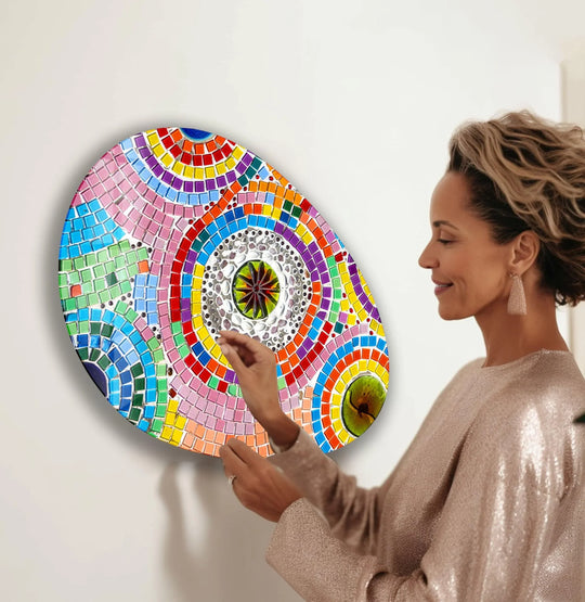 A woman smiles as she admires a vibrant oval mosaic glass wall art, a centerpiece of unique modern wall decor.