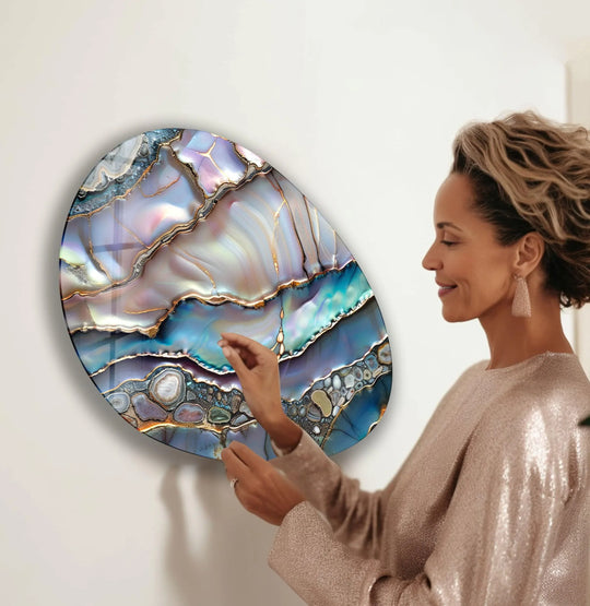 A woman admires the swirling, dynamic movement captured in this oval abstract glass wall art decor.