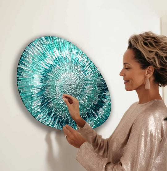 A woman admires a vibrant turquoise helix abstract oval hanging wall art with shades of teal and white.