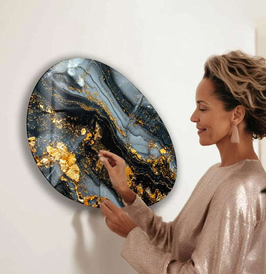 A woman admires the organic forms and swirling gray and gold patterns on a luxurious print wall art.