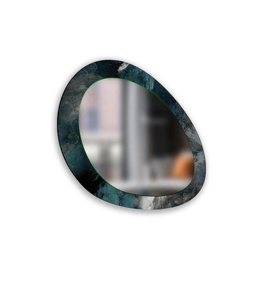 An abstract wall mirror with green and blue tones has an asymmetric oval shape reflecting a blurred room an entryway mirror
