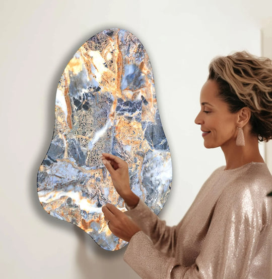 A woman with curly hair smiles at a marbled blue irregular print wall art with flowing lines and textures.