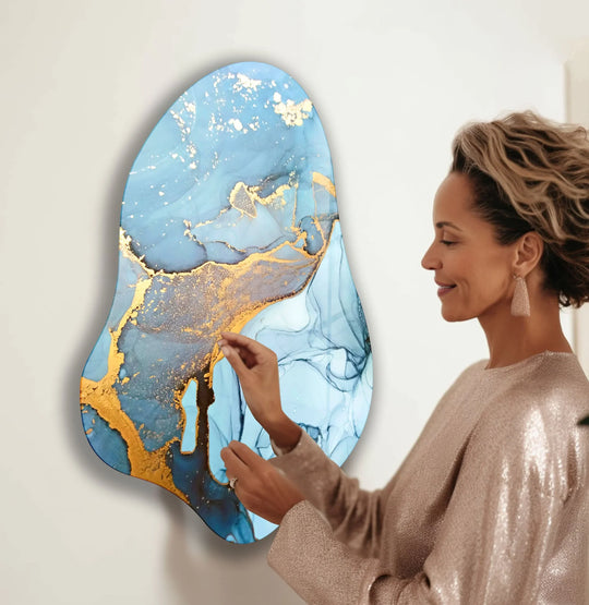 A woman in a sequined dress admires an abstract blue and gold glass wall artwork.