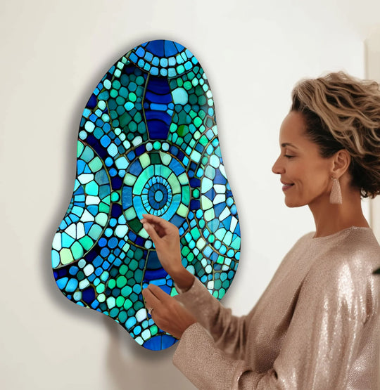 A woman admires a vibrant glass wall artwork with striking cool color contrast of deep blues and bright greens.