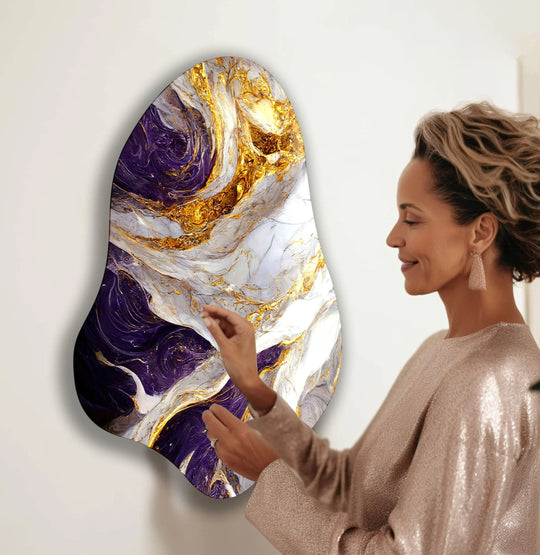 A woman admires a strikingly saturated purple and gold abstract glass wall art print with rich, vibrant marbling.