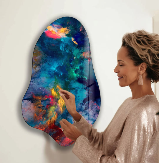 A woman admiring a stunning blue abstract glass wall art print with vibrant swirls of color.